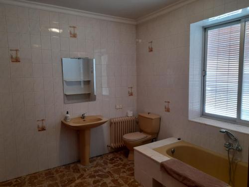 La salle de bains est pourvue de toilettes, d'un lavabo et d'une baignoire. dans l'établissement Magdeleine Village, à Almagro