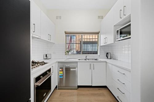 a white kitchen with a sink and a dishwasher at Burwood City Newly renovated 2 Bed 2 Bath Free Private Parking Big Apt in Sydney