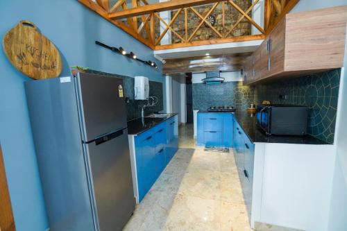 una cucina con armadi blu e frigorifero di The Apricity Bhimtal a Bhimtal