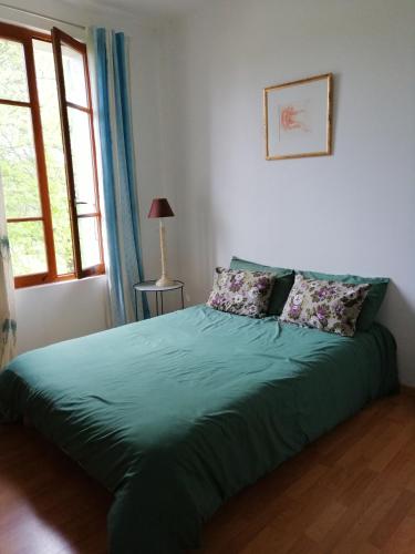 - une chambre avec un lit doté de draps verts et une fenêtre dans l'établissement La Campagne en Ville, à Laragne