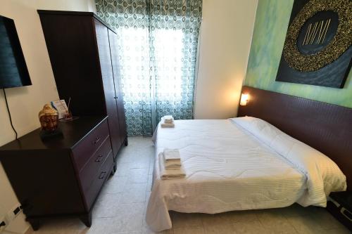 a bedroom with a bed and a dresser and a window at Hotel Okinawa in Rimini