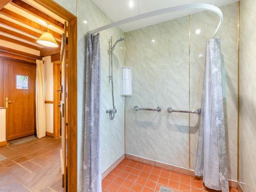 La salle de bains est pourvue d'une douche avec rideau de douche. dans l'établissement The Lodge, à Lydney