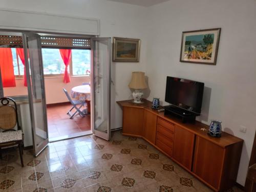 蒙德羅的住宿－Mondello Sunrise，客厅设有1个带电视和桌子的柜子和1张桌子
