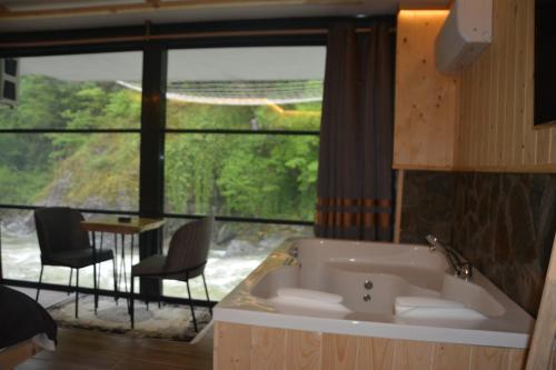 a bath tub in a room with a large window at DOĞAL SUİT BUNGALOV in Ardeşen