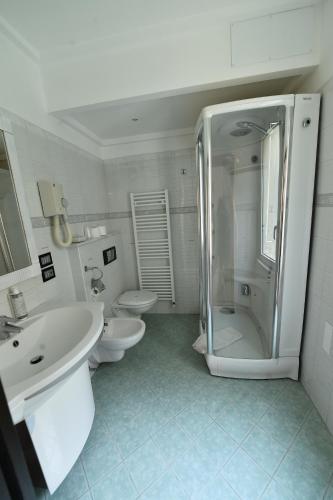 a white bathroom with two toilets and a shower at Hotel Okinawa in Rimini