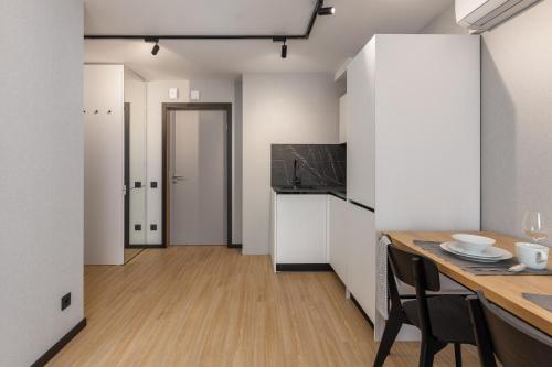 リガにあるBalcia Residenceの白いキャビネットと木製のテーブルのあるキッチン