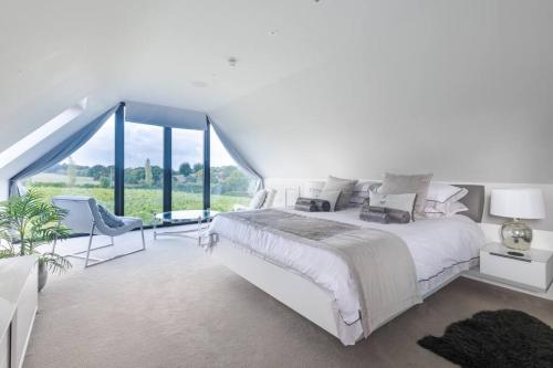 a white bedroom with a large bed and a large window at Toppesfield Vineyard luxury, contemporary villa - 2 adults in Toppesfield