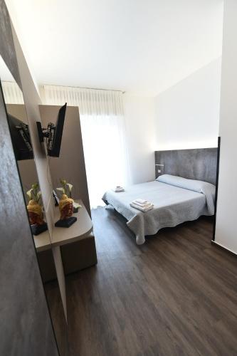 a small bedroom with a bed and a table at Hotel Okinawa in Rimini