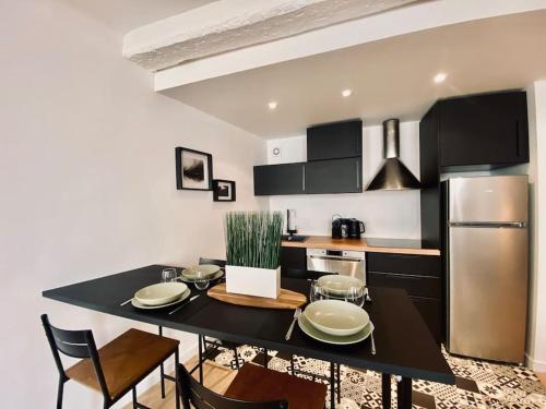 La cuisine est équipée d'une table noire et d'un réfrigérateur en acier inoxydable. dans l'établissement Appartement Centre ville, Cannes le Suquet, à Cannes