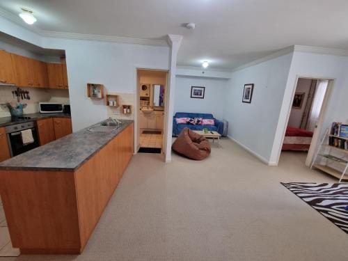 a kitchen with a counter and a living room at Little Monica Apartment- Spacious, Affordable & Central in Perth