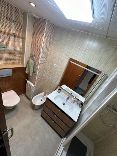 a bathroom with a sink and a toilet and a mirror at Duplex en centro de calella in Calella