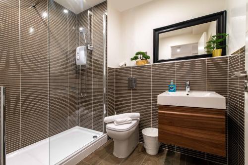 a bathroom with a toilet and a sink and a tub at Queens House Apartment in Coventry