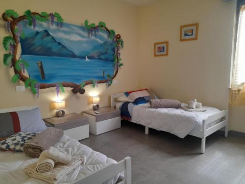Habitación con 2 camas y una pintura en la pared. en Villa La Magnolia - Private Beach Access, Garden, Views, en Lazise