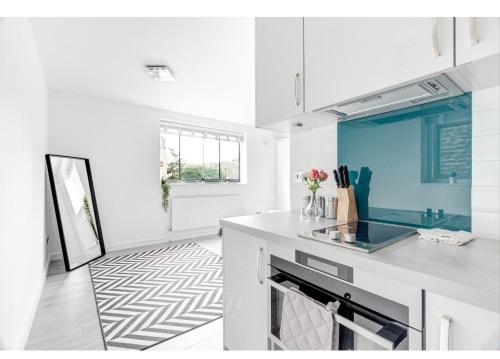 a kitchen with white cabinets and a blue wall at Sherborne Court in London