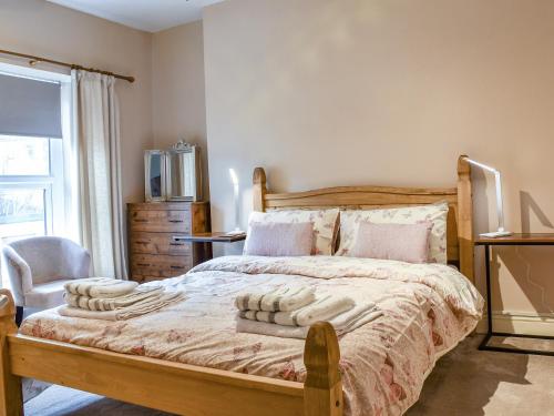 a bedroom with a bed and a chair and a window at Cwmcarn Cottage in Crosskeys