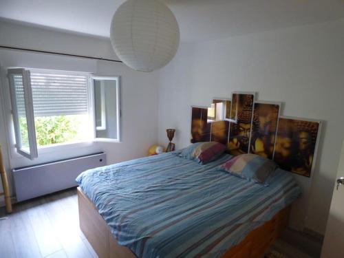 1 dormitorio con 1 cama con edredón azul y ventana en Maison spacieuse, quartier calme, piscine chauffe, en Cenon
