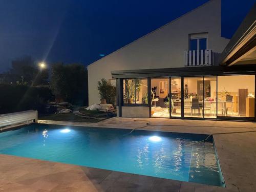 una piscina frente a una casa por la noche en Maison spacieuse, quartier calme, piscine chauffe, en Cenon