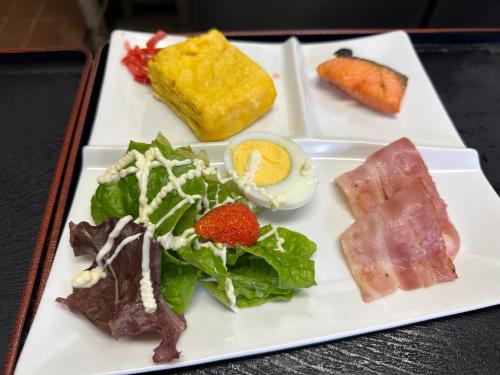 a white plate topped with different types of food at ゲストハウス れんげ苑 in Shimosato