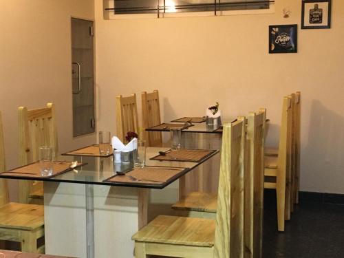 a dining room with a glass table and wooden chairs at Salora Kodai in Kodaikānāl