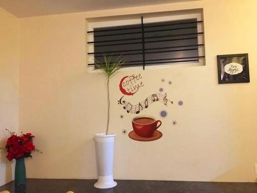 a plant in a white vase with a cup on a wall at Salora Kodai in Kodaikānāl