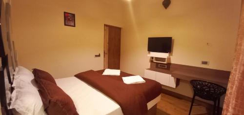 a hotel room with a bed and a television at Salora Kodai in Kodaikānāl