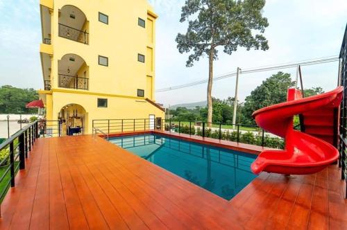 a red chair sitting on a deck next to a swimming pool at La Reina Maroc Hotel ปากช่อง เขาใหญ่ in Pak Chong