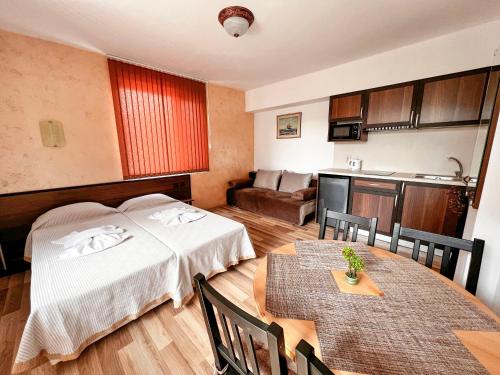 a room with two beds and a table and a kitchen at Chrystal Guest House in Obzor