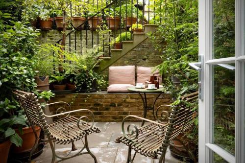 a patio with two chairs and a table with plants at Kings Cross, self-contained house & private garden in London
