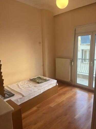 a bedroom with a bed and a large window at Two bedroom apartment in Historical area in Thessaloniki
