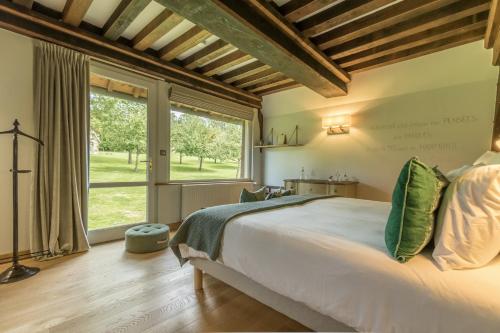 um quarto com uma cama grande e uma janela grande em Maisons d'hôtes - Domaine Le Coq Enchanté em Cambremer