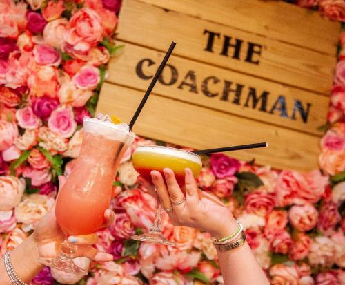 two people holding drinks in their hands in front of flowers at The Coachman Hotel in Kilsyth