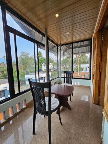a room with a table and chairs and windows at SKY BLUE HOMESTAY with POOL in Vythiri