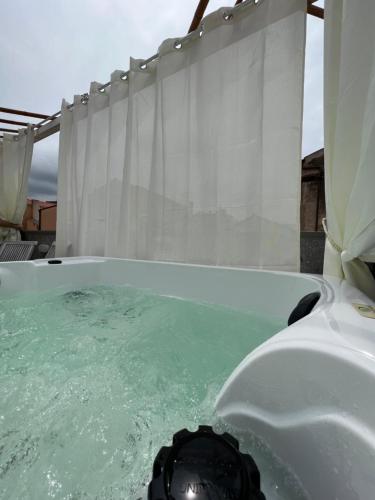 a bath tub filled with green water next to a shower at Regnos Altos boutique rooms in Bosa