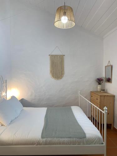 um quarto com uma cama branca e um lustre em Monte do Pereiro em Santiago do Cacém