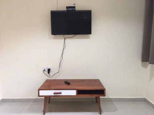 a table with a tv on a white wall at clp perai homstay near Sri Muniswarar Temple in Perai