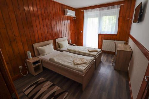 ein kleines Schlafzimmer mit 2 Betten und einem Fenster in der Unterkunft Vadkacsa Panzio in Balatonkenese