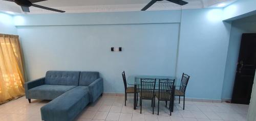 uma sala de estar com um sofá, uma mesa e cadeiras em Mandy Court Apartment em Kuala Lumpur