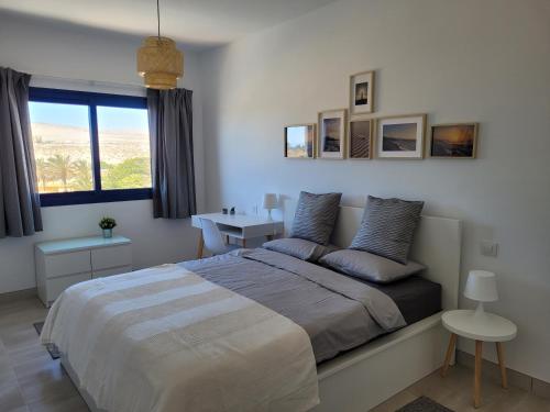 a bedroom with a bed and a desk and a window at Casa Nalu - Costa Calma Sun & Pool in Costa Calma