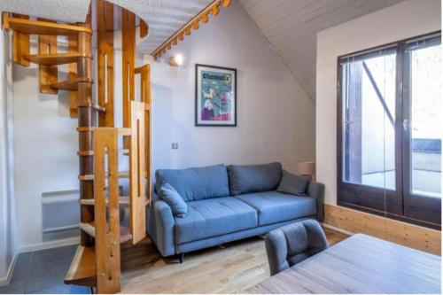 ein Wohnzimmer mit einem blauen Sofa und einer Leiter in der Unterkunft Triplex Aiguille du Midi furnished flat in Chamonix-Mont-Blanc