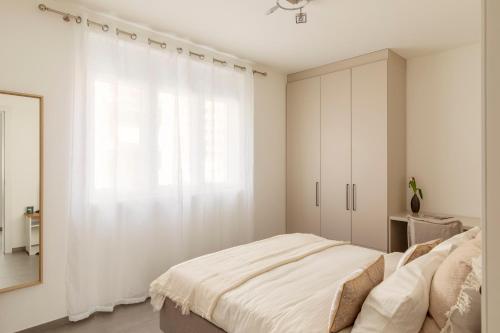 a white bedroom with a bed and a window at Lugano Superior Suites - Free Parking in Lugano