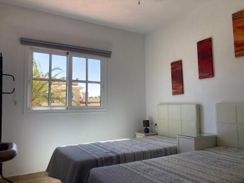 sypialnia z 2 łóżkami i oknem w obiekcie Las Rocas Golf and Sea w mieście Caleta De Fuste