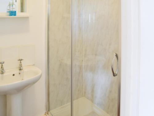 a shower with a glass door next to a sink at Cygnet Cottage - Uk43546 in Belford