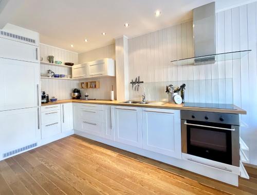 a white kitchen with white cabinets and a sink at Skottinden Panorama Lofoten in Ballstad