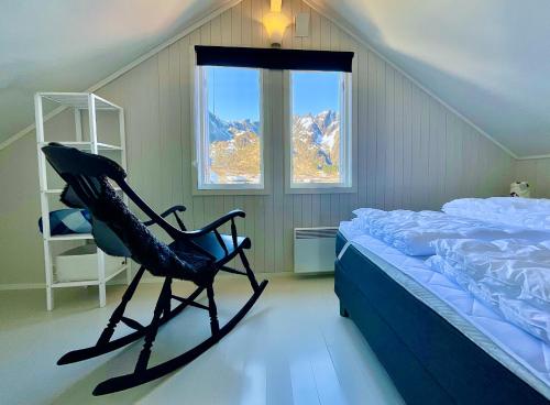 a bedroom with a chair next to a bed at Skottinden Panorama Lofoten in Ballstad
