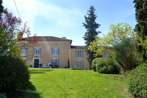 una grande casa con un prato verde davanti di Chambre d'hôte au Domaine Terre de Chênes a Saint-Paul-de-Baïse