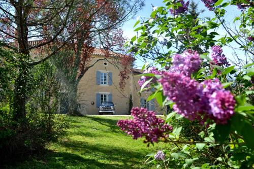 una casa con fiori viola di fronte a un cortile di Chambre d'hôte au Domaine Terre de Chênes a Saint-Paul-de-Baïse