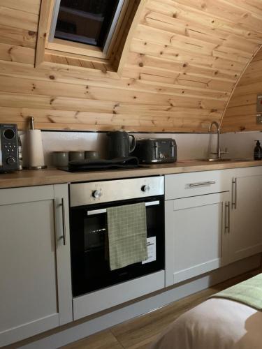 a kitchen with white cabinets and a stove top oven at Loch an Eilean Pod Isle of South Uist in Pollachar