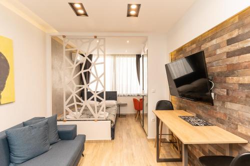 a living room with a couch and a table and a tv at Valaoritou Luxury Studio in Thessaloniki