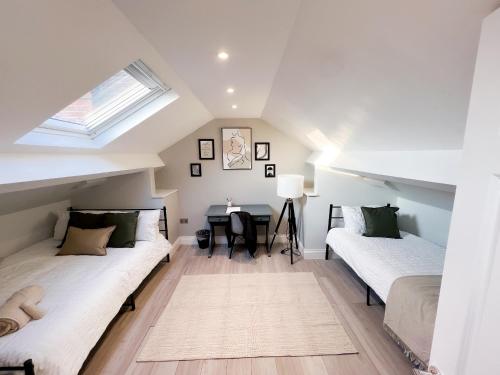 a attic bedroom with two beds and a table at Stylish 2 Bed Apt - Watford Gen Hospital - Watford FC - Professionals & Contractors Welcome in Watford