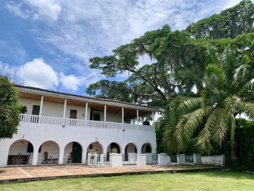 a white building with a palm tree in front of it at Rancho Saman in Pereira